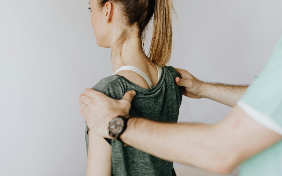 crop anonymous osteopath straightening shoulders of woman in doctor office